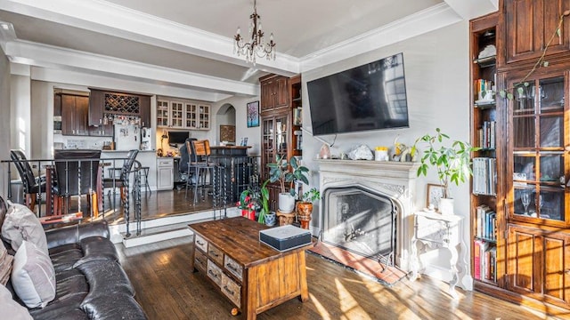 living area with dark wood-type flooring, crown molding, a fireplace, an inviting chandelier, and arched walkways