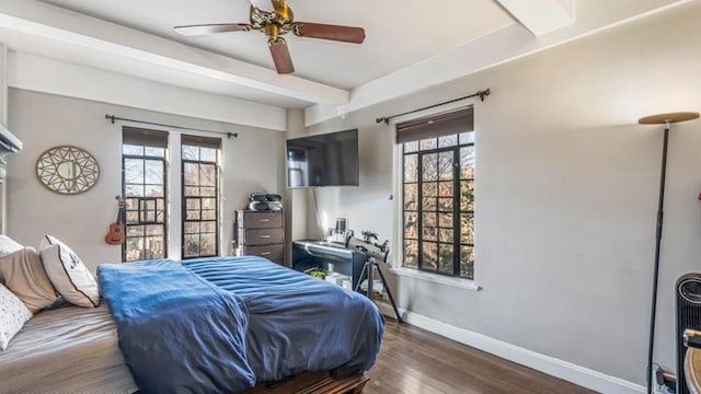 bedroom with baseboards, multiple windows, beamed ceiling, and wood finished floors