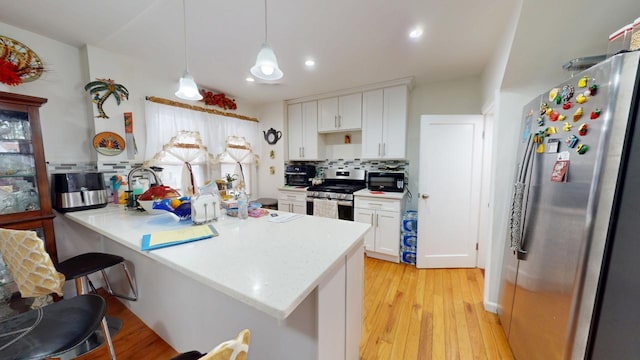 kitchen featuring decorative backsplash, appliances with stainless steel finishes, white cabinets, and a breakfast bar