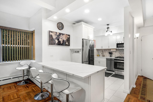 kitchen with light stone countertops, white cabinets, appliances with stainless steel finishes, a kitchen bar, and backsplash