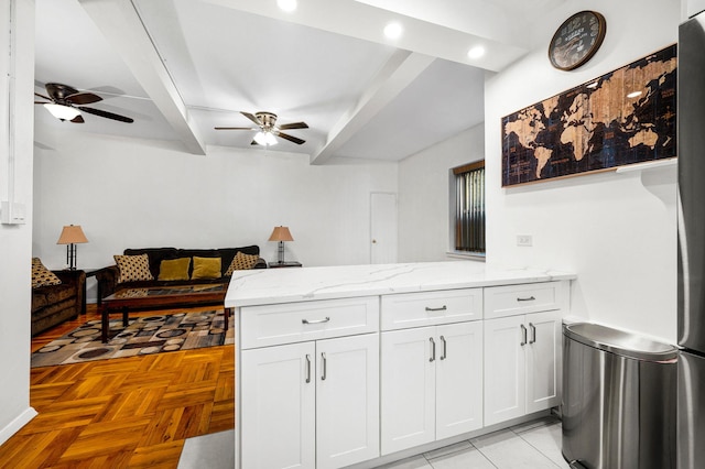 kitchen featuring light stone counters, white cabinets, a peninsula, and a ceiling fan