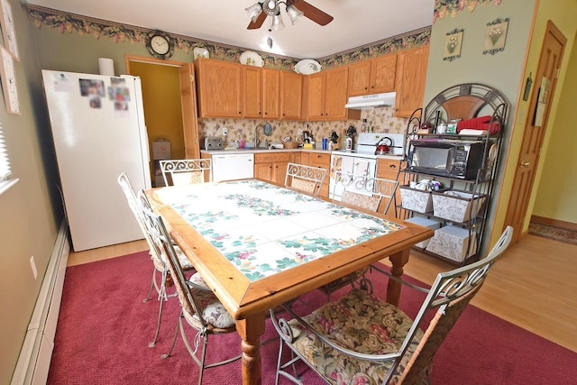 kitchen with white appliances, wood finished floors, a ceiling fan, light countertops, and under cabinet range hood