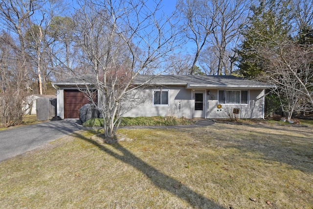 ranch-style home with aphalt driveway, an attached garage, and a front yard