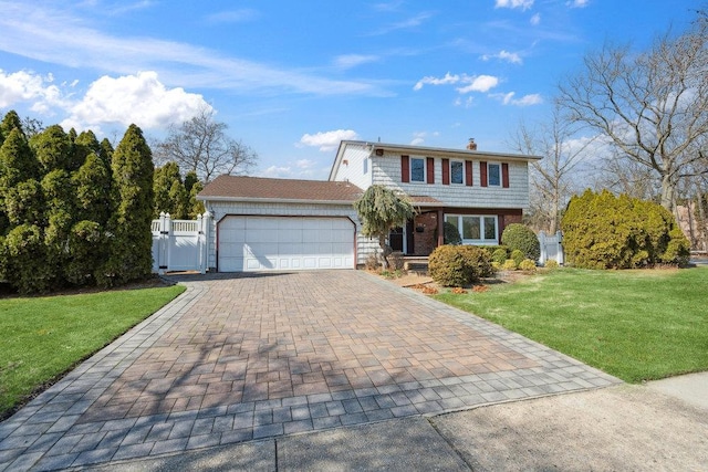 view of front of property with a gate, fence, an attached garage, a front lawn, and decorative driveway