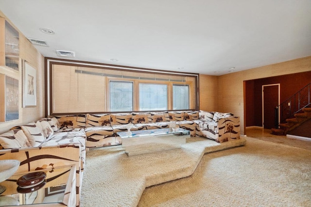 carpeted living area with stairs and visible vents