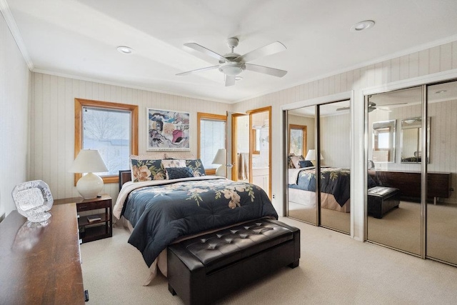 bedroom featuring ceiling fan, carpet flooring, two closets, and ornamental molding