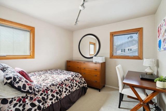 bedroom with light carpet, rail lighting, and baseboards