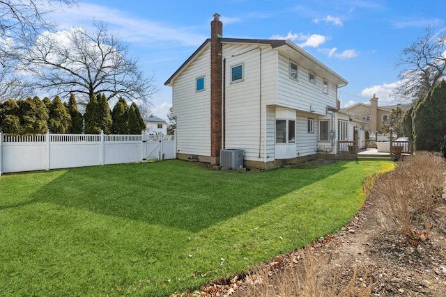 view of home's exterior featuring a lawn, cooling unit, a wooden deck, fence private yard, and a chimney