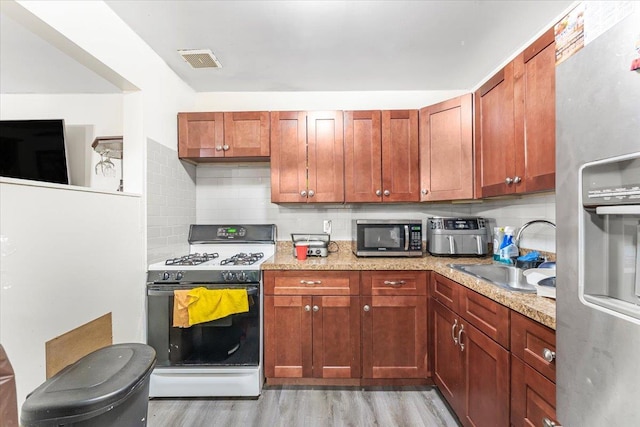 kitchen featuring tasteful backsplash, visible vents, light wood finished floors, stainless steel appliances, and a sink