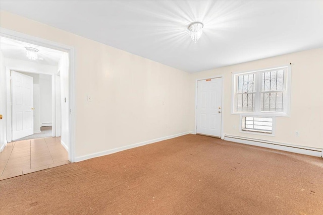 carpeted spare room featuring a baseboard heating unit and baseboards