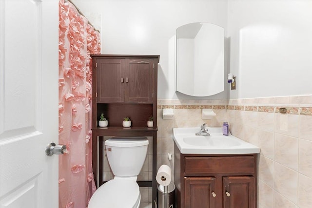 bathroom featuring tile walls, a wainscoted wall, toilet, and vanity