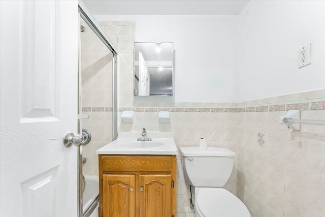 full bath with tile walls, toilet, vanity, and washtub / shower combination