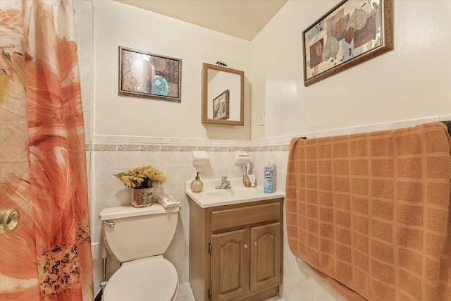 bathroom featuring vanity, toilet, tile walls, and wainscoting