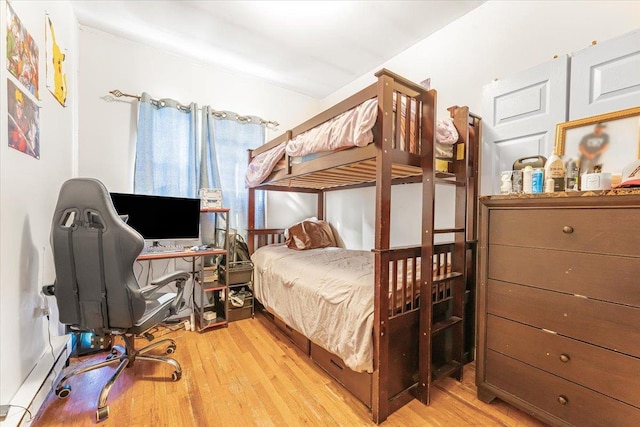 bedroom with baseboard heating and wood finished floors