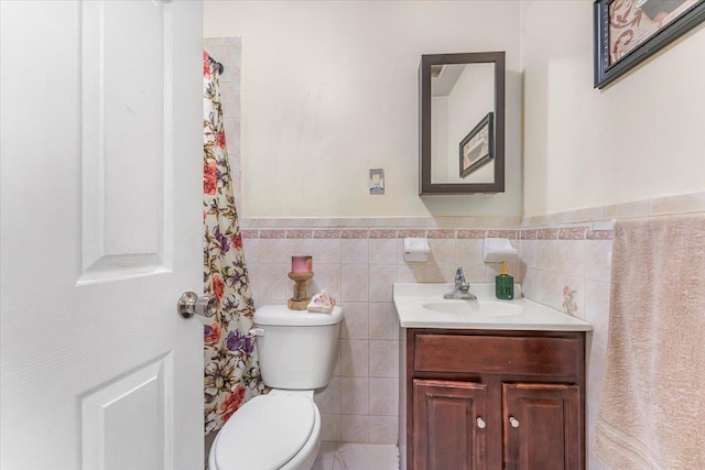 bathroom with wainscoting, toilet, vanity, and tile walls