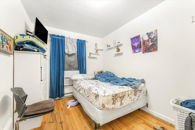 bedroom with cooling unit, wood finished floors, and baseboards