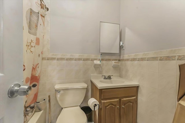 full bathroom featuring a wainscoted wall, toilet, tile walls, and vanity