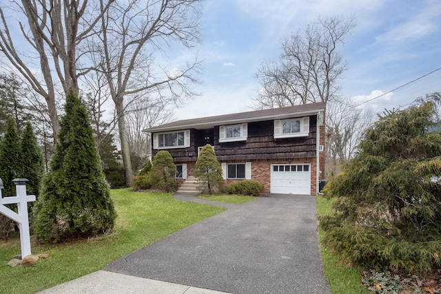 split foyer home with brick siding, driveway, an attached garage, and a front lawn