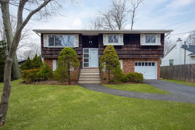 bi-level home with a front lawn, driveway, fence, a garage, and brick siding