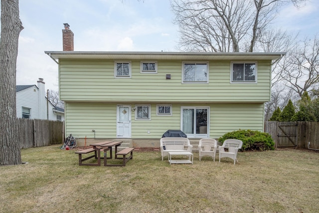 back of house featuring a yard, a fenced backyard, and a chimney