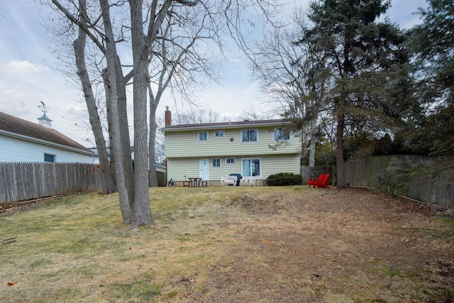 rear view of property with a lawn, fence private yard, and a chimney