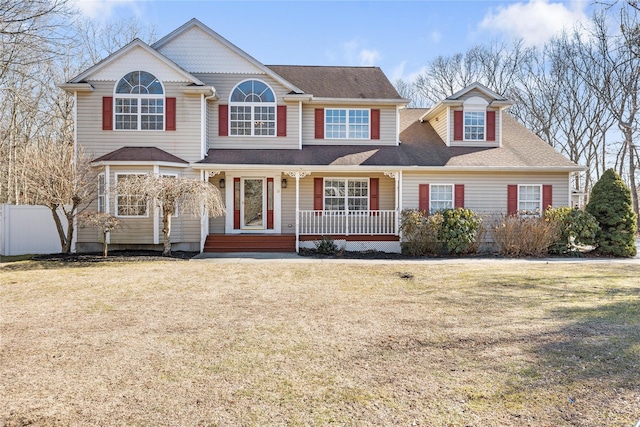 view of front of home with covered porch, a front yard, and fence