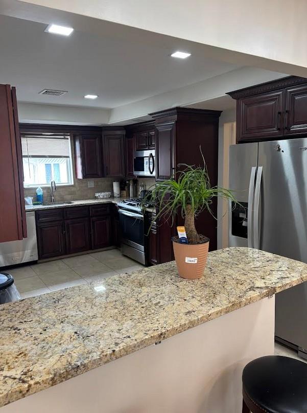 162-30 89th St, Howard Beach, NY 11414 - kitchen with a sink, tasteful backsplash, light stone countertops, appliances with stainless steel finishes, and visible vents