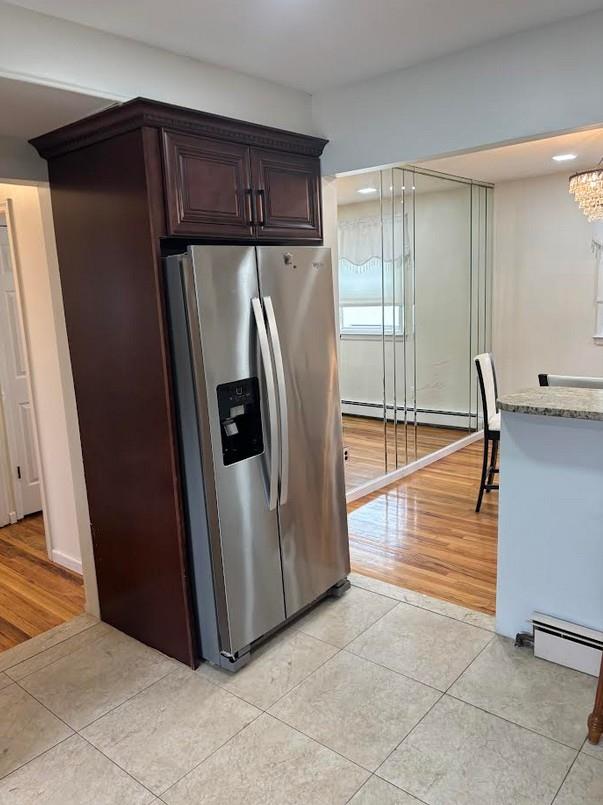 162-30 89th St, Howard Beach, NY 11414 - kitchen featuring stainless steel fridge with ice dispenser, light stone counters, light tile patterned floors, and baseboard heating