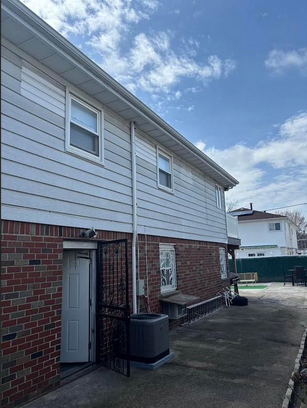 162-30 89th St, Howard Beach, NY 11414 - exterior space featuring brick siding, central air condition unit, fence, and a patio area