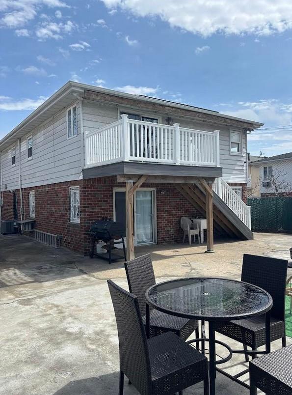 162-30 89th St, Howard Beach, NY 11414 - rear view of house featuring stairs, brick siding, a patio area, and outdoor dining space