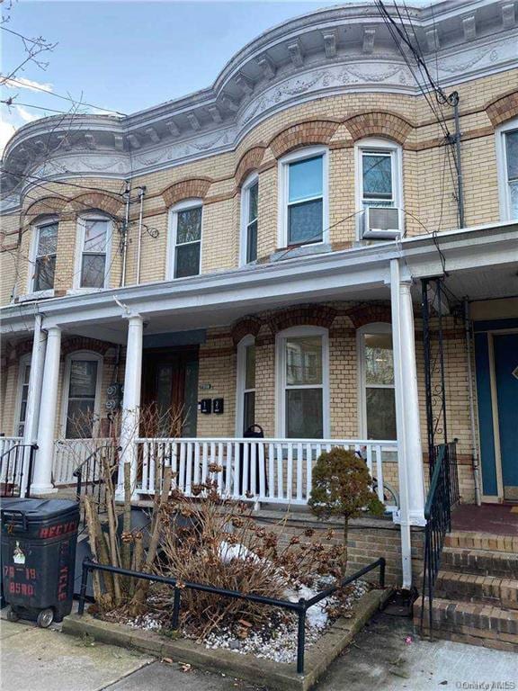 townhome / multi-family property with a porch and brick siding