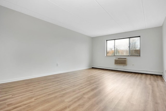 spare room featuring a baseboard radiator, baseboards, and light wood finished floors