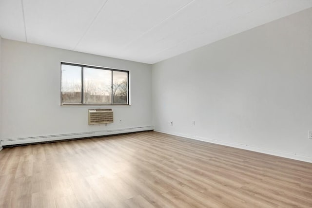 spare room featuring a wall mounted AC, light wood-style flooring, baseboards, and a baseboard radiator