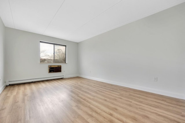 spare room featuring heating unit, baseboards, baseboard heating, and light wood-style flooring