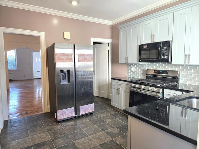 kitchen with backsplash, ornamental molding, dark stone countertops, appliances with stainless steel finishes, and arched walkways