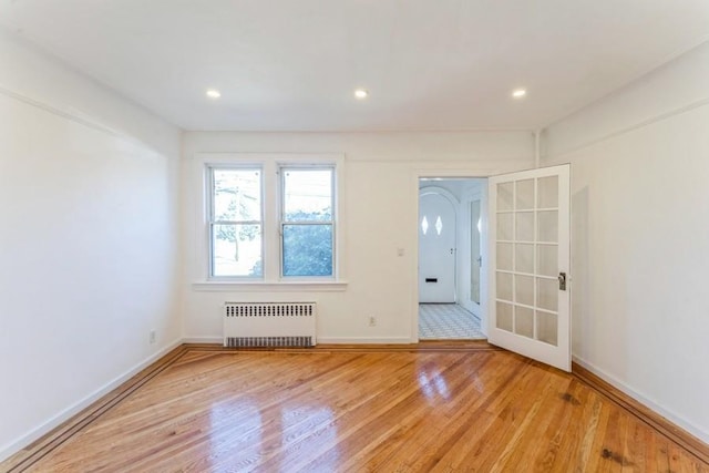 foyer featuring light wood-style flooring, radiator heating unit, recessed lighting, and baseboards