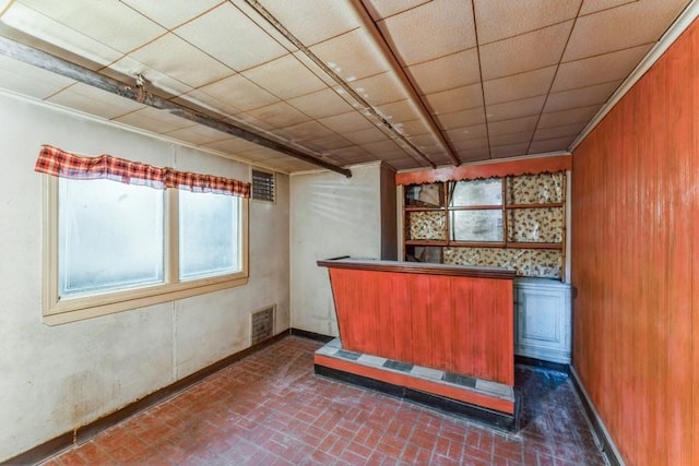 bar featuring visible vents, a bar, brick floor, and a drop ceiling