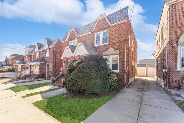 view of front of house with a high end roof, a detached garage, fence, a residential view, and brick siding