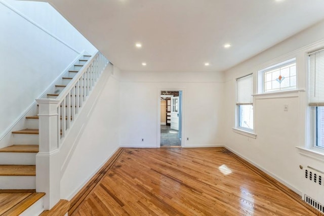 interior space featuring wood finished floors, recessed lighting, radiator, baseboards, and stairs