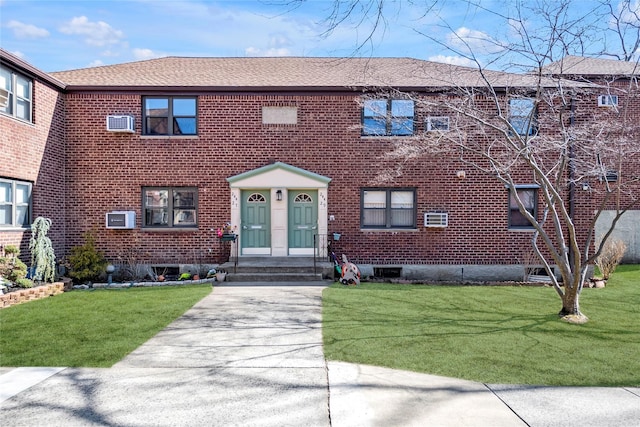 view of front of home with brick siding, a shingled roof, and a front yard