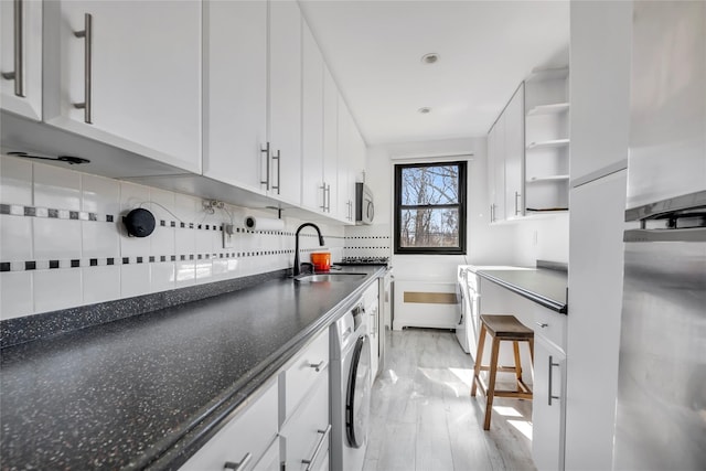 kitchen featuring stainless steel microwave, a sink, washer / clothes dryer, white cabinetry, and open shelves