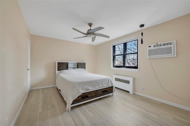 bedroom with baseboards, an AC wall unit, radiator heating unit, and light wood-style floors