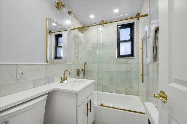 bathroom with vanity, tile walls, toilet, combined bath / shower with glass door, and backsplash