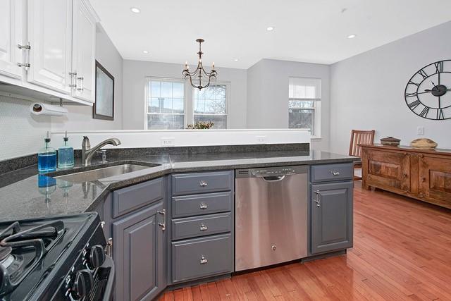 kitchen featuring dishwasher, a peninsula, a sink, and gray cabinetry