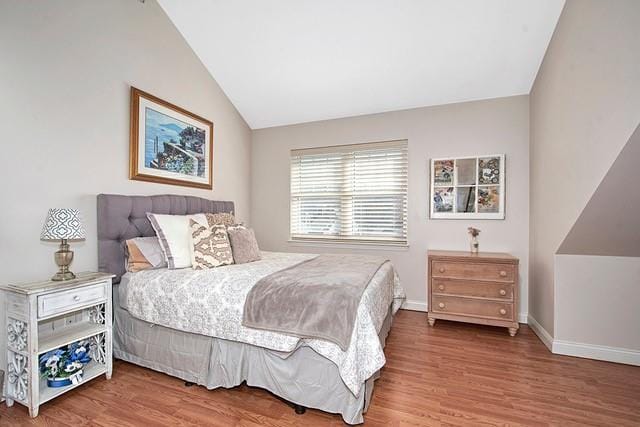 bedroom featuring baseboards, wood finished floors, and vaulted ceiling