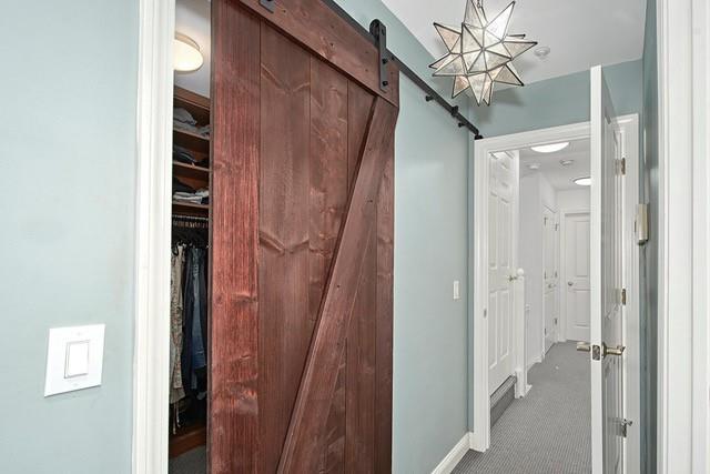 corridor with a barn door, baseboards, and carpet