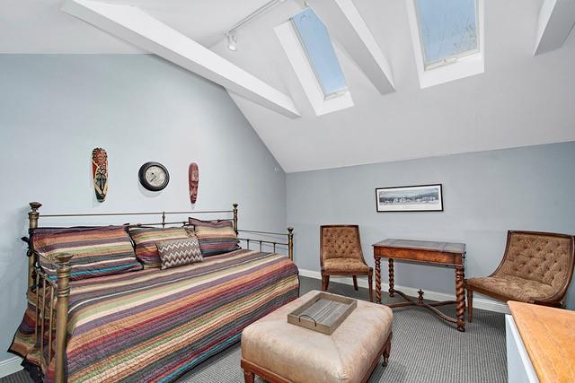 bedroom featuring baseboards, vaulted ceiling with skylight, carpet, and rail lighting