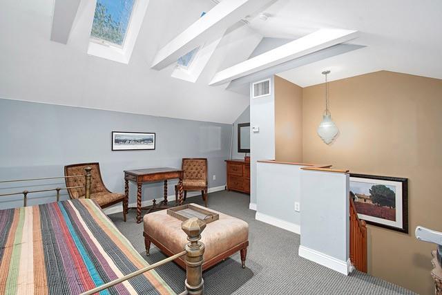 sitting room with lofted ceiling with skylight, carpet flooring, baseboards, and visible vents