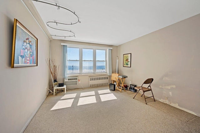 sitting room with a wall unit AC, radiator heating unit, and carpet