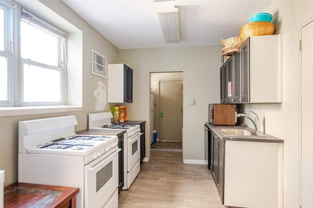 kitchen featuring light wood-style flooring, white range with gas stovetop, baseboards, and a sink